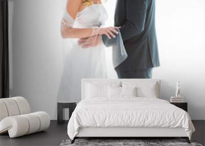 beautiful bride in white wedding dress, and groom in elegant black suit standing face to face isolated on white Wall mural