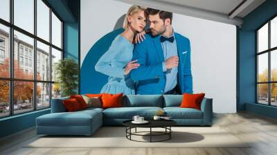 beautiful couple in stylish blue suit and dress standing together in aperture on grey Wall mural