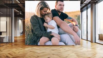 beautiful happy family with one child sitting together outdoors Wall mural