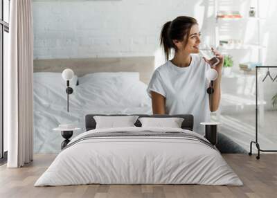 beautiful happy girl holding drinking water from glass in the morning Wall mural