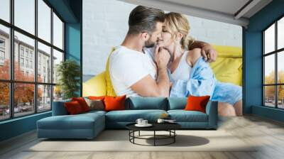 beautiful happy young couple in love hugging and kissing on couch Wall mural