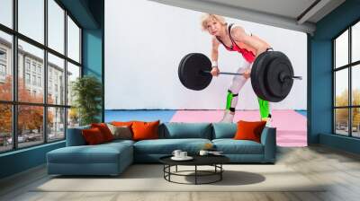 beautiful sportive senior lady lifting barbell and looking at camera Wall mural