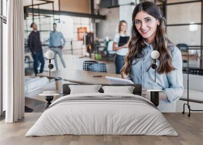 beautiful young businesswoman using digital tablet and smiling at camera in office Wall mural