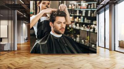 Beautiful young hairdresser cutting hair to handsome man in beauty salon Wall mural