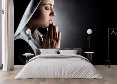 beautiful young nun with closed eyes praying with cross on grey Wall mural