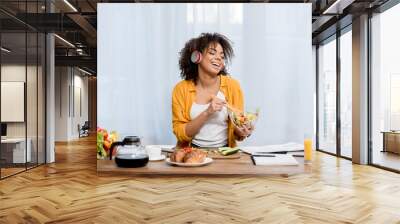 beautiful young woman listening music and preparing salad at kitchen Wall mural