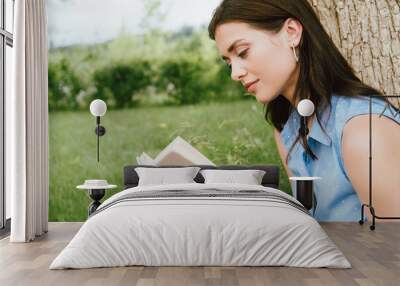 beautiful young woman reading book outside Wall mural