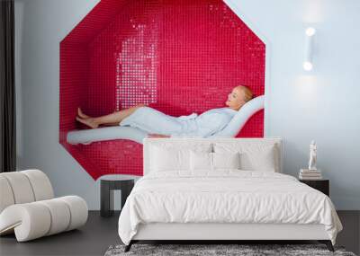 blonde woman lying on white deck chair in mosaic octagon Wall mural