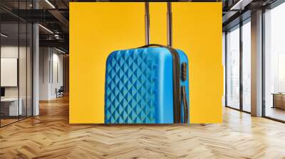 blue plastic travel bag with handle on wheels isolated on orange Wall mural