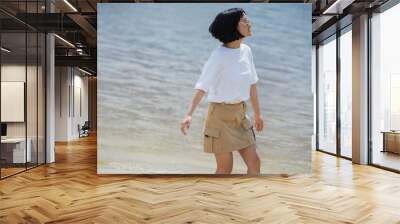 brunette asian woman in white t-shirt and beige skirt posing near river. Wall mural