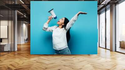 brunette asian woman screaming in loudspeaker on blue background Wall mural