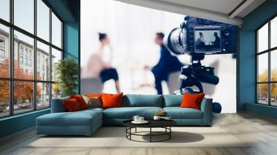 businessman giving interview to journalist in office, camera on tripod on foreground Wall mural