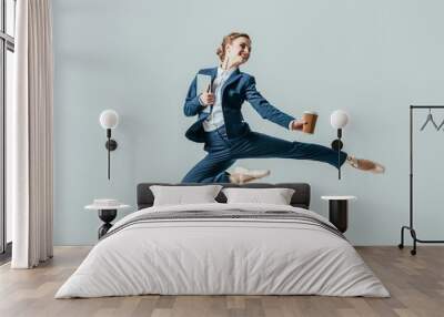 businesswoman in suit and ballet shoes jumping with coffee and digital tablet, isolated on grey Wall mural