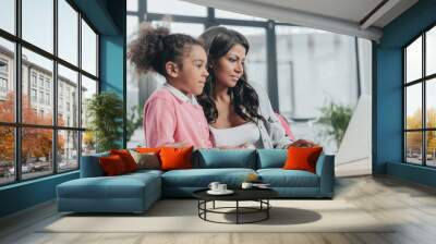 businesswoman typing on laptop with daughter near by, work and life balance concept Wall mural