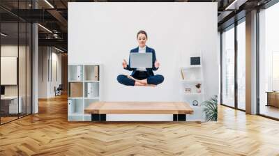 businesswoman using laptop while levitating in office Wall mural