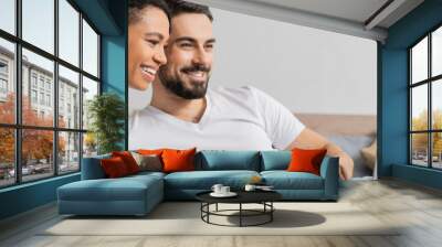 carefree multiethnic couple in white t-shirts watching film on laptop at home, banner. Wall mural