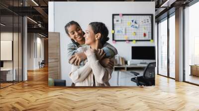 cheerful african american mother and daughter looking at each other while embracing at home Wall mural