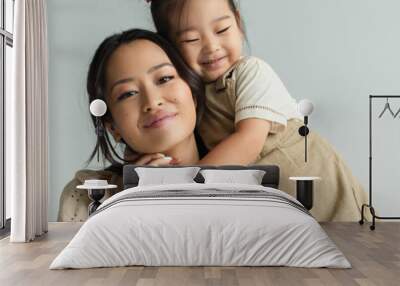 cheerful asian toddler daughter hugging happy mother isolated on gray, banner Wall mural