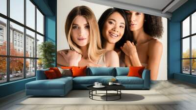 cheerful asian woman hugging blonde model near african american friend isolated on white Wall mural