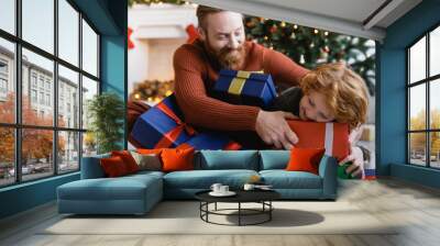 cheerful bearded man and redhead child having fun with Christmas gift boxes at home Wall mural