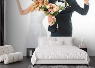 cheerful bride and groom waving hands while looking at camera isolated on white Wall mural