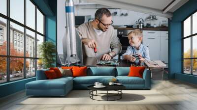 cheerful father and son repairing circuit board and looking at each other at home Wall mural