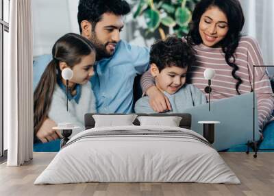 cheerful hispanic family looking at laptop at home Wall mural