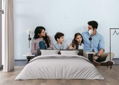 cheerful hispanic family sitting on floor near white wall Wall mural