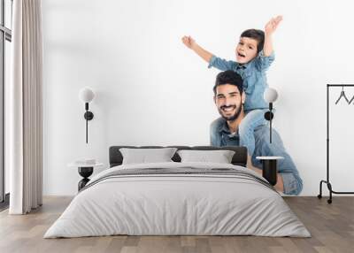 Cheerful kid sitting on shoulders of hispanic father isolated on white, two generations of men Wall mural