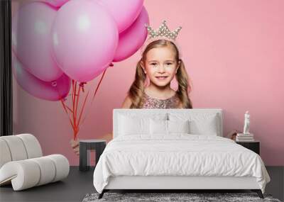 cheerful little girl in dress and crown holding balloons isolated on pink Wall mural