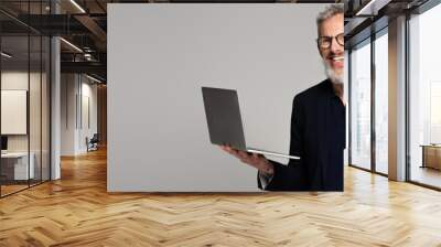 cheerful middle aged man in glasses holding laptop isolated on grey, banner Wall mural