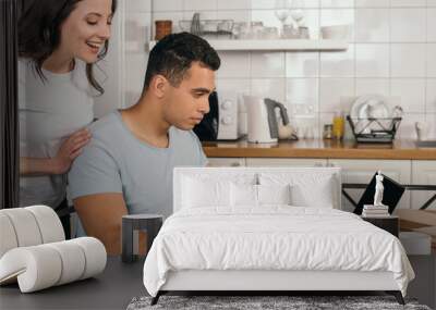 cheerful woman standing near mixed race boyfriend holding pen near laptop with blank screen Wall mural