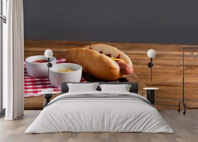 chopping board with hot dog, ketchup and mustard in bowls on wooden table isolated on grey Wall mural