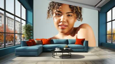 Close-up of an active African American woman with curly hair against a vibrant backdrop. Wall mural