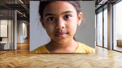 close-up portrait of a child girl looking curiously at the camera, with rack focus drawing attention to the child's face, leaving the background softly faded Wall mural