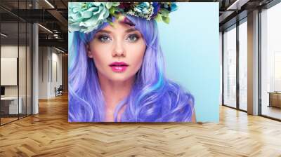 close-up portrait of beautiful young woman with curly blue hair and floral wreath isolated on blue Wall mural