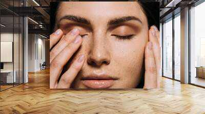 close up view of tender girl with freckles on face touching closed eyes Wall mural