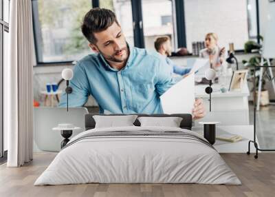 concentrated young businessman working with papers and laptop in office Wall mural