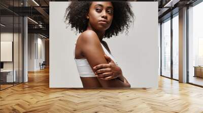 Confident African American woman with curly afro hair standing with arms crossed, exuding strength and empowerment. Wall mural