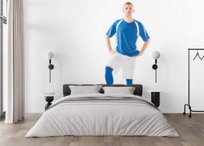 confident young soccer player standing with hands on hips and looking at camera isolated on white Wall mural