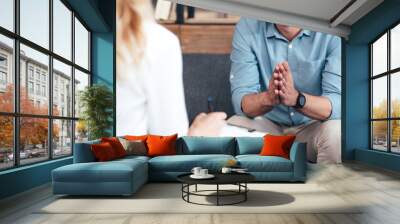 cropped image of female counselor writing in clipboard and smiling male holding hand palms together during therapy session in office Wall mural