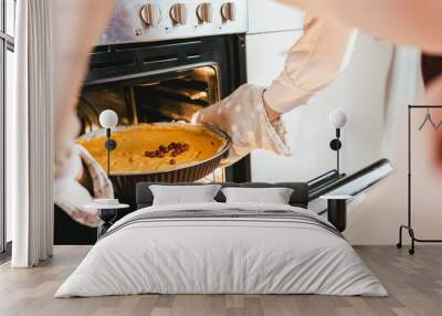 cropped shot fo woman taking out pumpkin pie from oven Wall mural