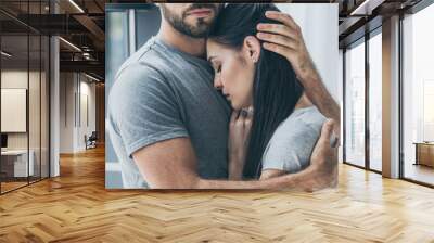 cropped shot of bearded man hugging and supporting young sad woman Wall mural