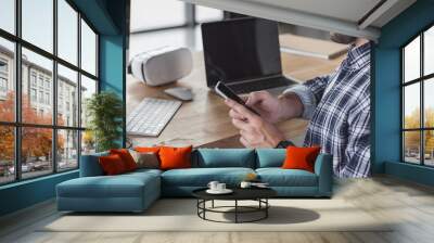 cropped shot of smiling man using smartphone while sitting at workplace Wall mural