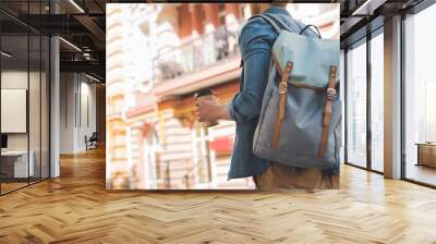 cropped shot of young man with backpack and coffee to go walking by street Wall mural