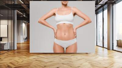 cropped view of beautiful slim woman in underwear posing with hands on hips isolated on grey Wall mural