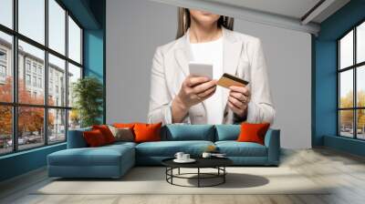 cropped view of businesswoman with grey hair shopping online with credit card and smartphone isolated on grey Wall mural