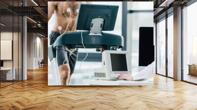 cropped view of doctor conducting endurance test with sportsman in gym Wall mural