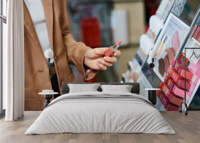 cropped view of elegant woman in business casual attire choosing new lipstick in cosmetics store Wall mural