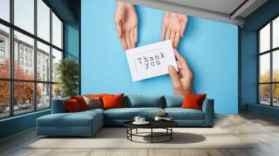 cropped view of man giving white card in frame with thank you lettering to woman on blue background Wall mural